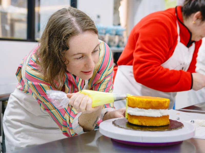 A woman concentrates on a beautiful cake at a baking class