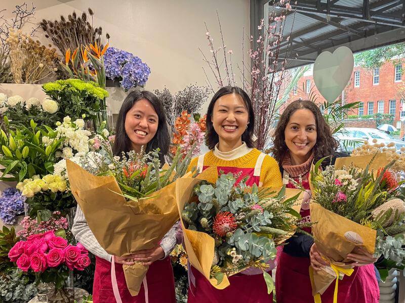 Three friends smile with their wildflower arrangements