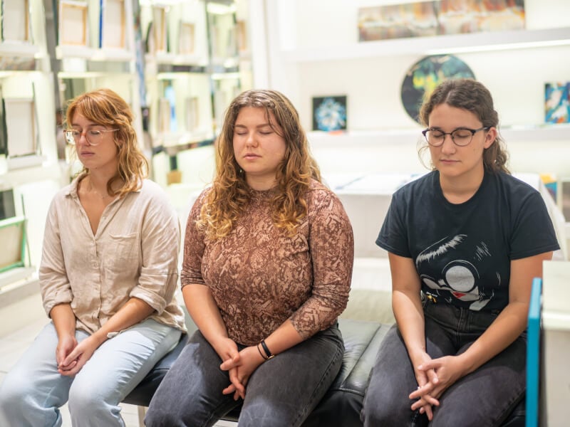 Three coworkers with their eyes closes engaging in a guided meditation session for team building