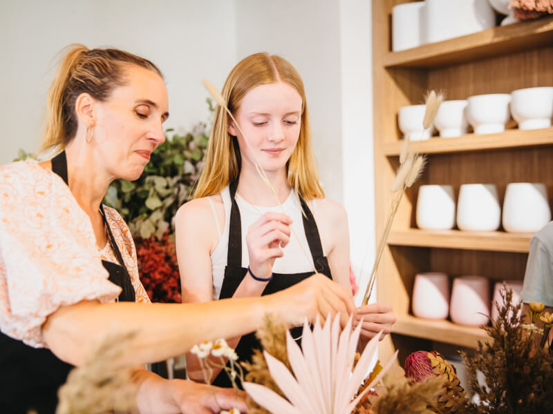 A young girl arranges flowers with her mum